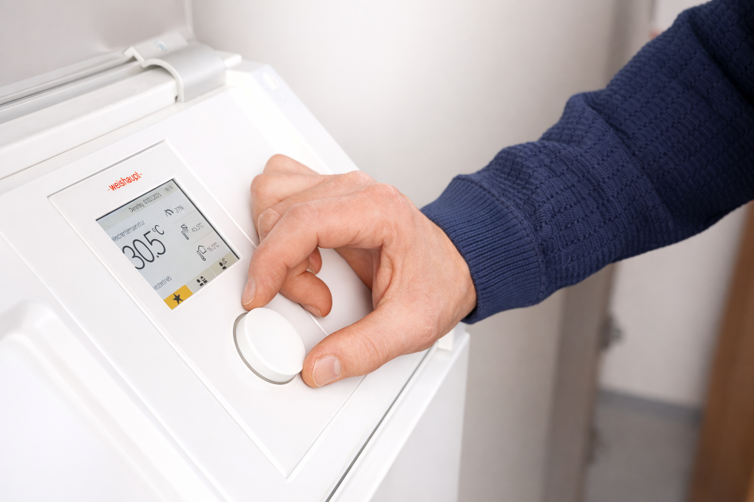Hand bedient das Display einer Weishaupt-Heizung, angezeigt werden 30,5 Grad